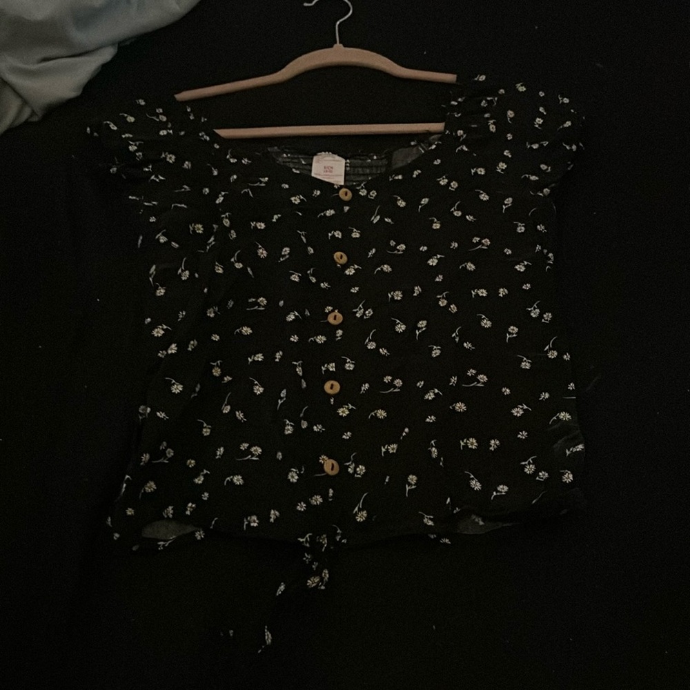 Black shirt with flower design and a little tie at the bottom.